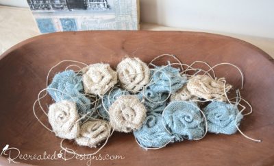Blue and beige burlap flowers in a wooden bread bowl
