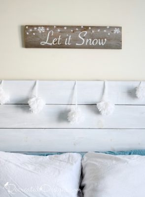 bedroom headboard dcorated with pom pom snowballs and a let it snow sign