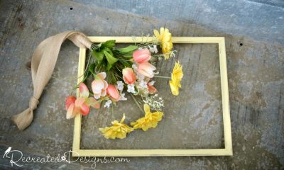 adding flowers to a picture frame to make a wreath