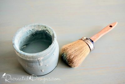 a glass jar filled with paint and a paint brush