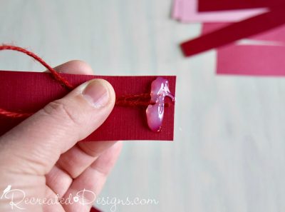 attaching a string hanger to a paper heart by Recreated Designs