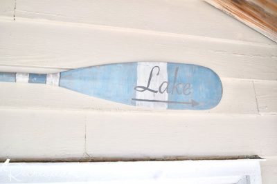 a blue and white Miss Mustard Seed Milk Painted paddle hanging on a cottage wall
