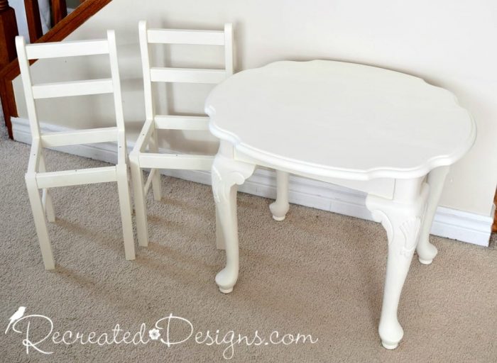 A mismatched side table and two small chairs painted with Country Chic Paint in Vanilla Frosting