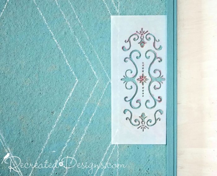using a stencil to add a pattern to a painted cork board