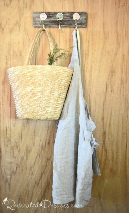 linen apron hanging from an upcycled piece of wood and vintage milk caps