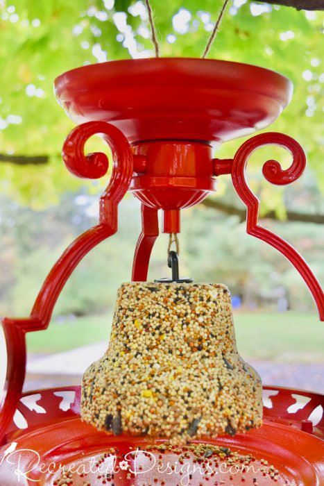 handing a bell of birdseed from a bird feeder