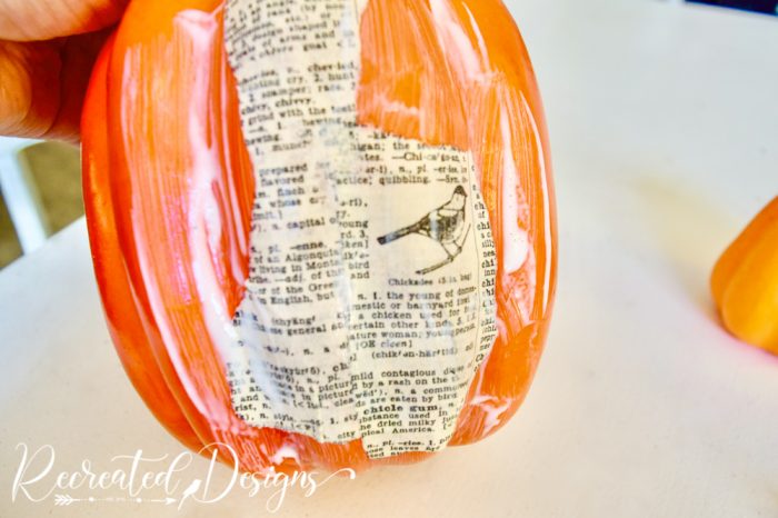 decoupaging book pages onto pumpkin