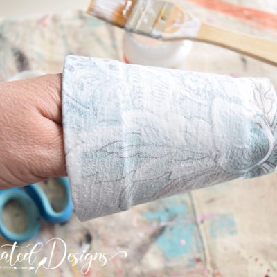 putting a coat of Mod Podge over fabric on a flower pot