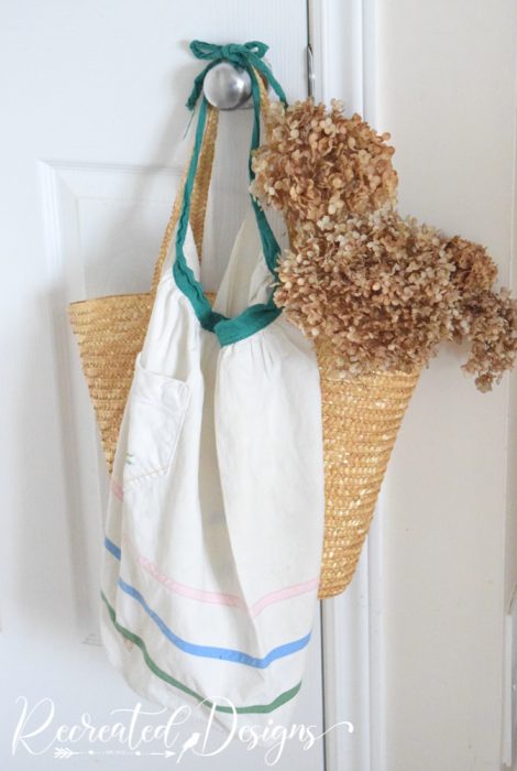 vintage apron hanging on door with bag and flowers