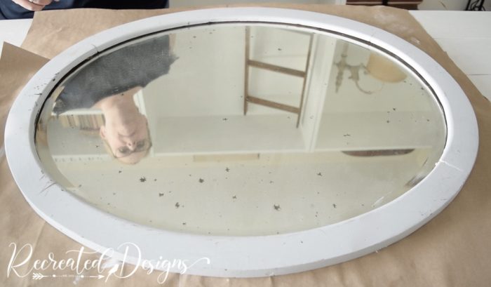 an old oval mirror with chippy glass