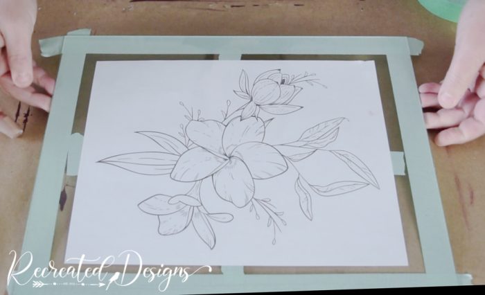 taping a print out of flowers to the back of a piece of glass