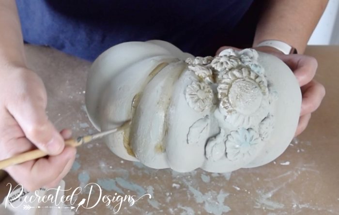 putting antiquing glaze into the crevices of a pumpkin
