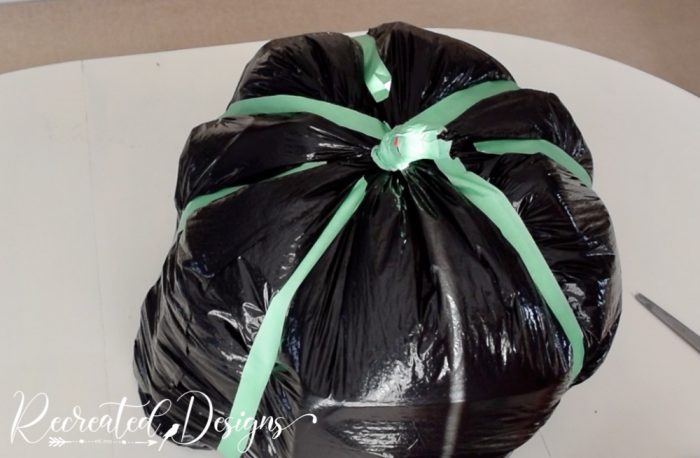 using painters tape to turn a black garbage bag into a giant pumpkin