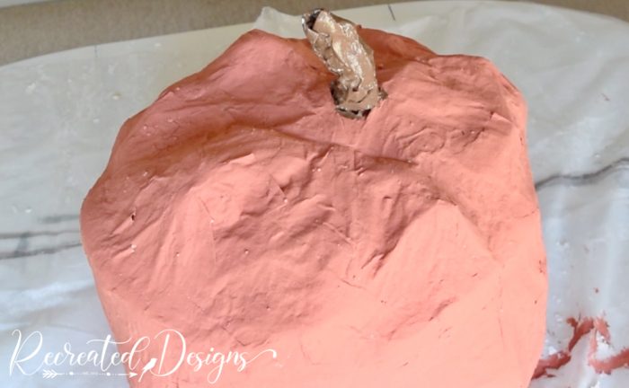 a giant paper mache pumpkin painted orange