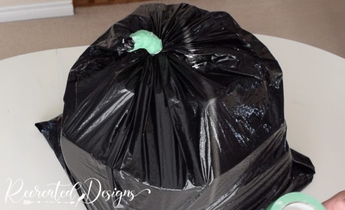 twisting the top of a garbage bag to make a pumpkin stem